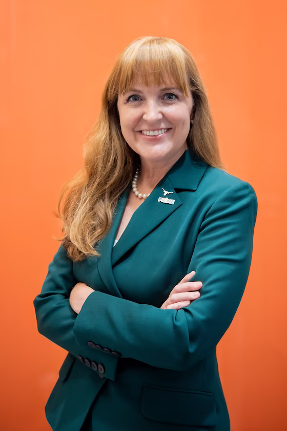 Light-haired white woman wearing a emerald green blazer